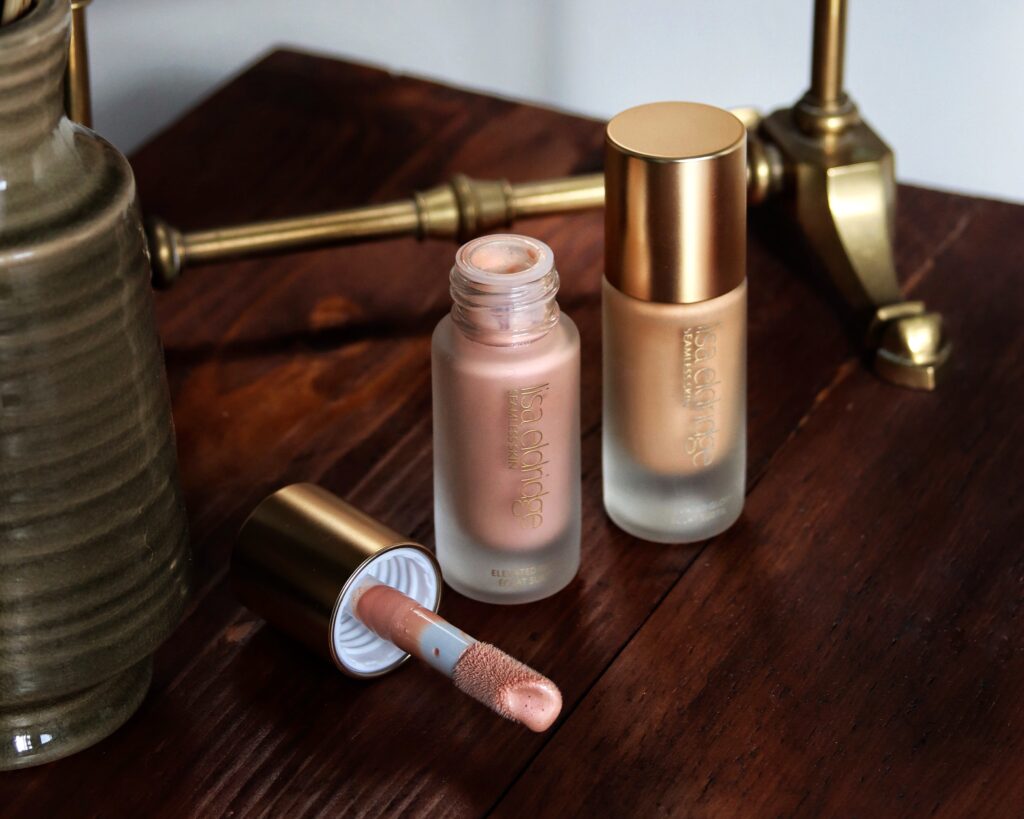 Lisa Eldridge Elevated Glow Highlighter - a review of two shades of this cruelty free liquid highlighter. In this image both glass bottle stand nect to each other, one has the lid off with a doe foot showing.