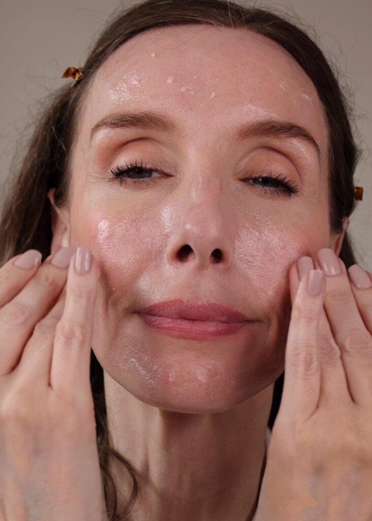 Amy is massaging the cleansing balm onto her skin showing how it breaks down makeup